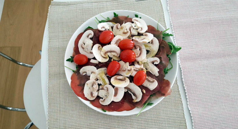 Insalata di rucola, bresaola, pomodorini e funghi champignon crudi